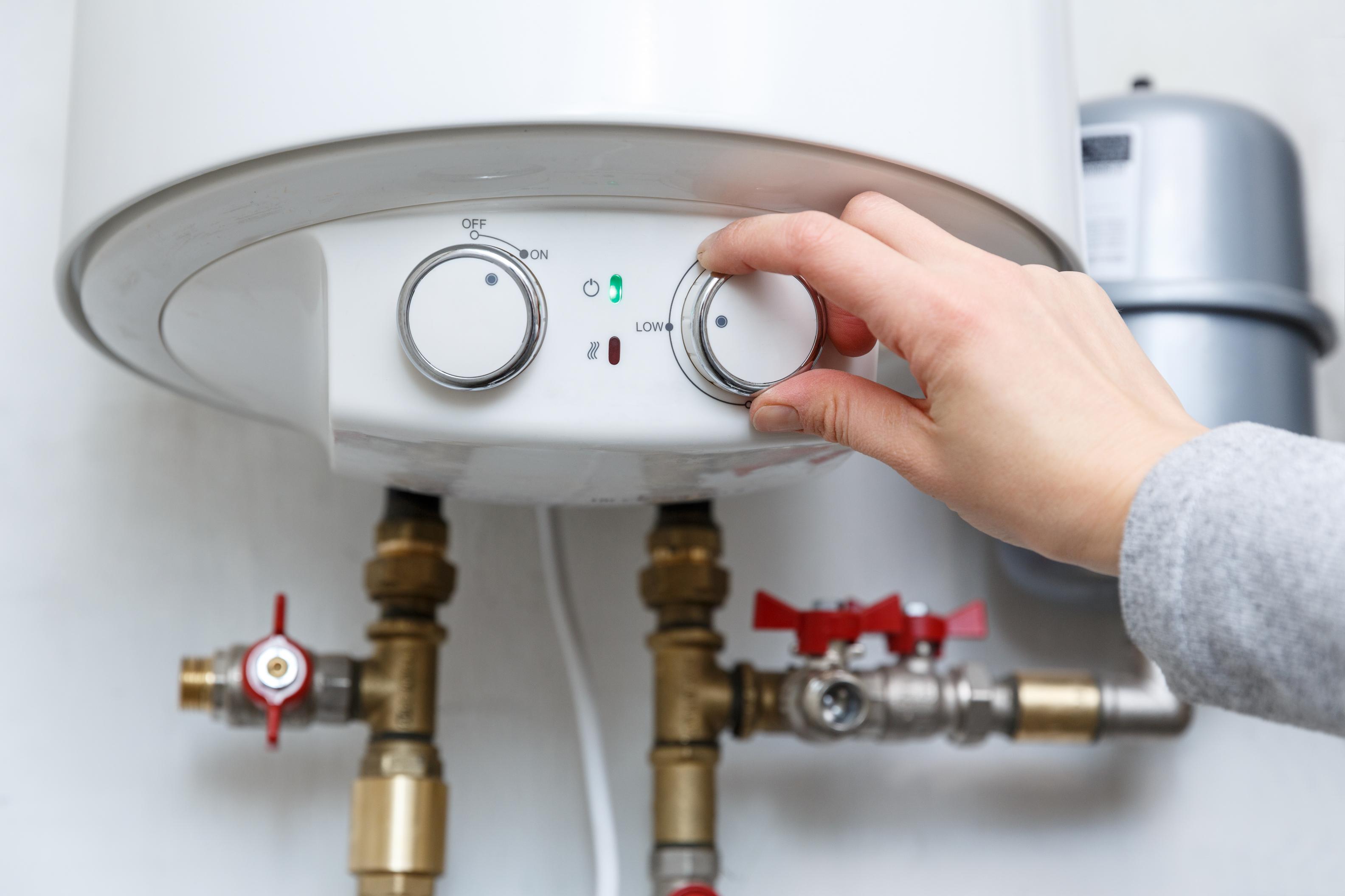 Plumber repairing the thermostat on an electric water heater